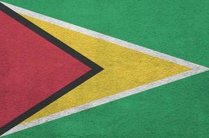 drapeau de la guyane représenté dans des couleurs de peinture vives sur un vieux mur de plâtrage en relief. bannière texturée sur fond rugueux photo