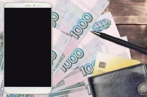 Factures de 1000 roubles russes et smartphone avec sac à main et carte de crédit. paiements électroniques ou concept de commerce électronique. achats en ligne et affaires avec des appareils portables photo