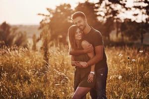 dans le champ éclairé par la lumière du soleil. beau jeune couple passe un bon moment dans la forêt pendant la journée photo