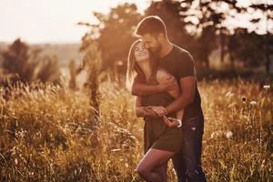 dans le champ éclairé par la lumière du soleil. beau jeune couple passe un bon moment dans la forêt pendant la journée photo