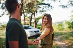 tenant par les mains. beau jeune couple passe un bon moment dans la forêt pendant la journée photo