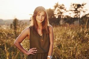 portrait d'une fille heureuse qui se tient dans le champ éclairé par la lumière du soleil photo