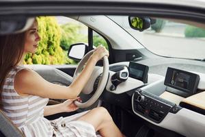 vue de côté. conductrice à l'intérieur d'une automobile moderne. tester une voiture neuve photo