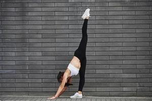 jeune brune sportive avec une forme de corps mince contre un mur de briques dans la ville pendant la journée photo