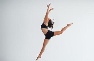 photo en mouvement. jeune femme sportive en vêtements noirs avec un type de corps mince dans le centre sain faisant des exercices