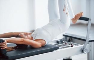 bon pour la colonne vertébrale. jeune femme sportive confiante avec un type de corps mince dans le centre sain faisant des exercices en utilisant un équipement spécial photo