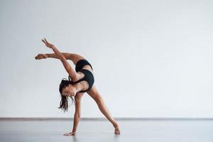 souplesse du corps humain. jeune femme sportive en vêtements noirs dans le centre sain faisant des exercices photo