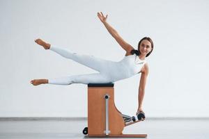 penché sur le côté. jeune femme sportive confiante avec un type de corps mince dans le centre sain faisant des exercices en utilisant un équipement spécial photo