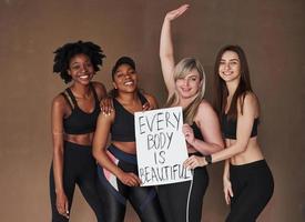 pas de complexes. groupe de femmes multiethniques debout dans le studio sur fond marron photo