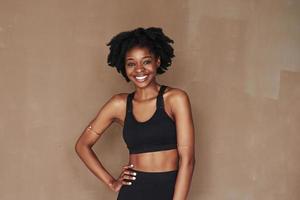 fille joyeuse. jeune belle femme afro-américaine en studio sur fond marron photo