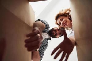 prendre des vêtements de la boîte. couple heureux ensemble dans leur nouvelle maison. conception du déménagement photo