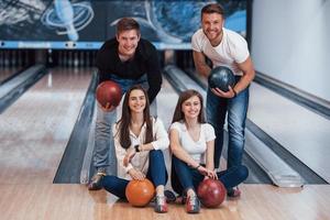 joli portrait. de jeunes amis joyeux s'amusent au club de bowling le week-end photo