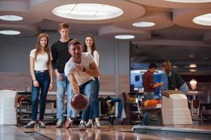 lancer de balle. de jeunes amis joyeux s'amusent au club de bowling le week-end photo