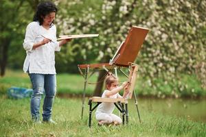 Bon travail. apprendre à peindre à sa petite-fille. dans le parc naturel photo