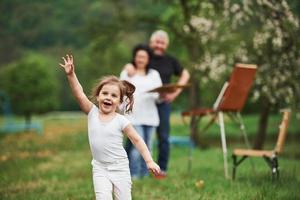 courir en avant. grand-mère et grand-père s'amusent dehors avec sa petite-fille. conception de la peinture photo