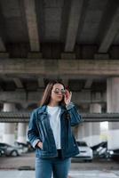 dans des vêtements en jean. portrait d'une belle jeune femme debout sous le pont à l'extérieur photo