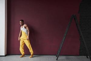 le temps de se reposer et de danser. jeune travailleur afro-américain en uniforme jaune a du travail photo