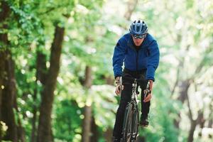 l'adrénaline est dans le sang. cycliste sur un vélo est sur la route goudronnée dans la forêt aux beaux jours photo