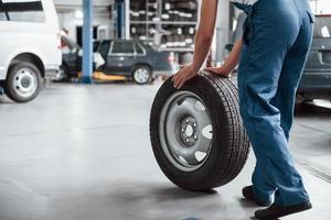 vue de derrière. employé dans l'uniforme de couleur bleue travaille dans le salon de l'automobile photo