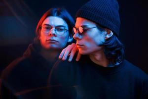 belles personnes. portrait de frères jumeaux. tourné en studio dans un studio sombre avec néon photo