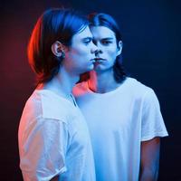 comme rétroviseur. portrait de frères jumeaux. tourné en studio dans un studio sombre avec néon photo