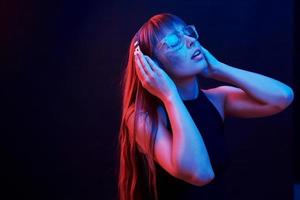 profiter de la musique. studio tourné en studio sombre avec néon. portrait de jeune fille photo