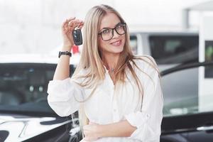 ce sont vos clés maintenant. le jeune directeur de l'atelier automobile se dresse contre une voiture noire parfaitement polie photo