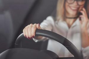 ongles rouges au centre de la caméra. femme en tenue officielle essayant sa nouvelle voiture dans un salon automobile photo