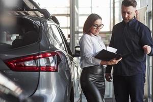 donnez votre signe ici. directeur adjoint donnant des conseils et de l'aide au client dans un salon automobile photo