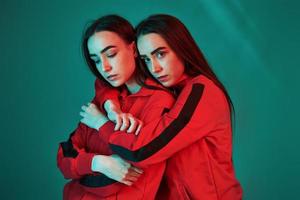 essayer de nouvelles vestes rouges. studio tourné à l'intérieur avec une lumière au néon. photo de deux beaux jumeaux