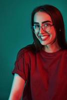 sourire à pleines dents. studio tourné à l'intérieur avec une lumière au néon. portrait de belle jeune fille photo