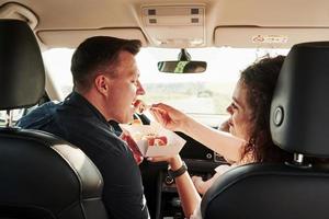 mange des sushis. de belles personnes sont dans la voiture moderne le week-end photo