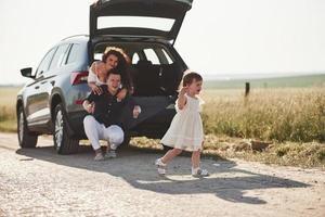 se sentir libre. la famille passe du bon temps à la campagne près de l'automobile argentée au coucher du soleil photo