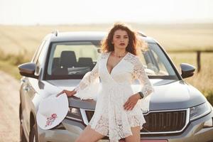 fille en vêtements blancs posant près de l'extérieur de l'automobile de luxe moderne photo
