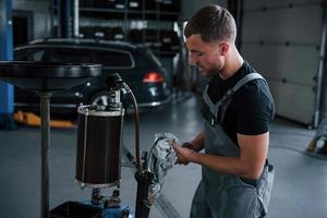 le militaire nettoie les instruments. un mécanicien masculin utilise un appareil spécial pour réparer une voiture cassée dans un garage photo