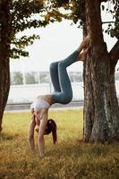 passer utilement les week-ends d'été. jeune femme au corps mince fait des exercices dans le parc photo