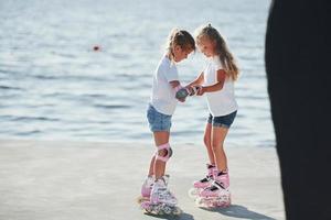 deux enfants apprennent à monter sur des patins à roulettes pendant la journée près du lac photo