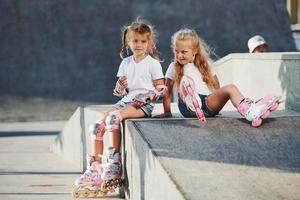 sur la rampe pour les sports extrêmes. deux petites filles avec des patins à roulettes à l'extérieur s'amusent photo