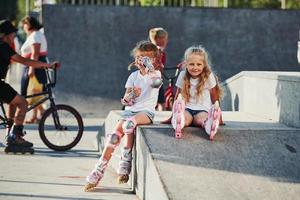 sur la rampe pour les sports extrêmes. deux petites filles avec des patins à roulettes à l'extérieur s'amusent photo