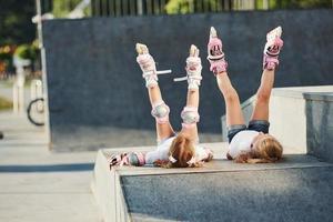 les jambes en l'air. se sentir libre. sur la rampe pour les sports extrêmes. deux petites filles avec des patins à roulettes à l'extérieur s'amusent photo