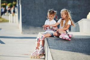 sur la rampe pour les sports extrêmes. deux petites filles avec des patins à roulettes à l'extérieur s'amusent photo