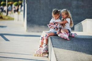 sur la rampe pour les sports extrêmes. deux petites filles avec des patins à roulettes à l'extérieur s'amusent photo