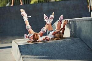 les jambes en l'air. se sentir libre. sur la rampe pour les sports extrêmes. deux petites filles avec des patins à roulettes à l'extérieur s'amusent photo