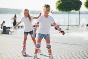 deux enfants mignons à cheval sur des patins à roulettes dans le parc pendant la journée photo