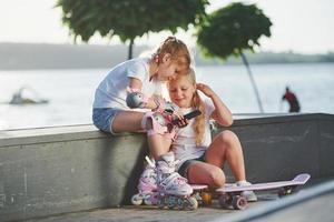 parler les uns avec les autres. sur la rampe pour les sports extrêmes. deux petites filles avec des patins à roulettes à l'extérieur s'amusent photo