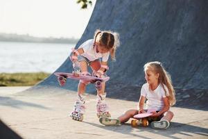 essayer un nouveau patin. deux jolies filles s'amusent dehors dans le parc photo