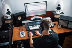 ingénieur du son dans les écouteurs travaillant et mélangeant de la musique à l'intérieur du studio photo