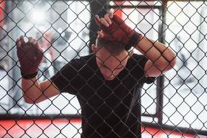 faire une pause. le sportif au ring de boxe fait de l'exercice. appuyé sur la clôture photo