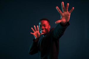s'amuser. éclairage néon futuriste. jeune homme afro-américain dans le studio photo