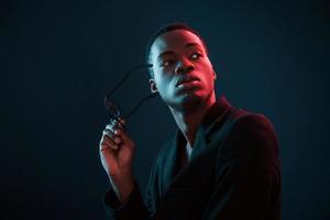 mannequin. éclairage néon futuriste. jeune homme afro-américain dans le studio photo